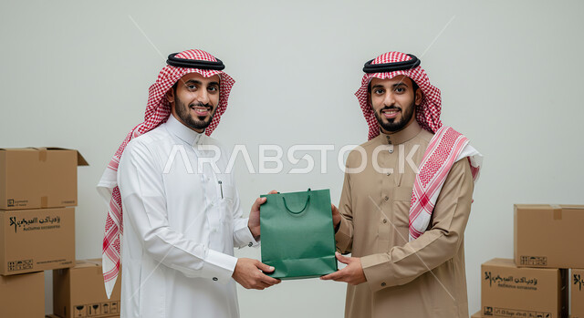 E-commerce concept, express delivery services, relying on online purchases, ordering products online, portrait of a Saudi Arabian Gulf man wearing a traditional thobe and shemagh taking a paper bag from a delivery man, delivering orders to customers easily and quickly, white background