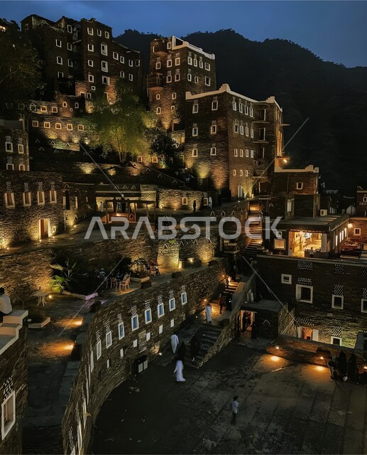 الفن الهندسي المعماري للمباني على الطراز القديم في مدينة أبها، معالم وأماكن سياحية مشهورة في المملكة العربية السعودية، قرية رجال ألمع الأثرية في منطقة عسير، أبنية حجرية بنوافذ خشبية مضيئة في الليل، جذب واستقطاب السياح من أنحاء العالم