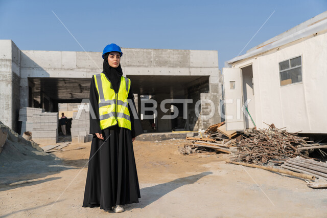 الاشراف على أعمال البناء وصب الخرسانات ووضع الأساسات الأولية، مهنة ووظيفة نسائية، مهندسة عربية خليجية سعودية محجبة ترتدي السترة والخوذة تقوم بمتابعة مبنى قيد الإنشاء والتشييد، مفهوم الهندسة الانشائية والمعمارية، إمرأة اماراتية تقف في موقع البناء
