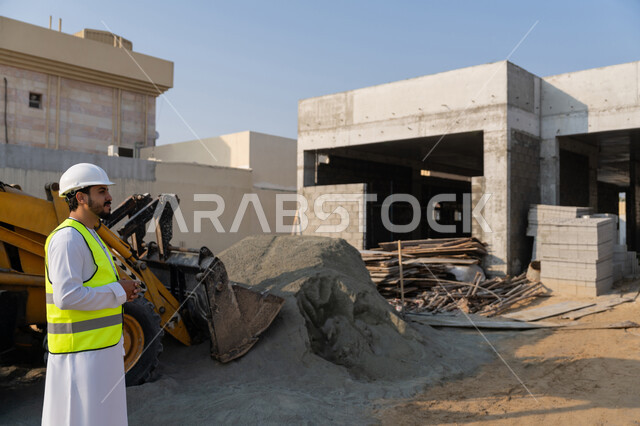 مهنة ووظيفة هندسية شبابية، مهندس عربي خليجي اماراتي يرتدي الكندورة والسترة وخوذة الحماية يعمل في القطاع الهندسي في الامارات العربية المتحدة، الاشرف على عمليات البناء، مفهوم ادارة المشاريع الهندسية والانشاءات، دراسة المخطط والمشروع على ارض الواقع
