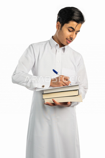 بورتريه لطالب جامعي عربي خليجي سعودي يحمل بيد مجموعة من الكتب  ، مستمتع بقراءة الكتاب الجامعي ،تدوين الملاحظات ، حل الواجبات ،المذاكرة للاختبارات الجامعية ، مراجعة الدروس اليومية ، التعليم الجامعي في المملكة العربية السعودية