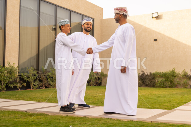 ايماءات الفرح و السرور, المحادثة والدردشات بين أفراد العائلة, ولد عربي خليجي عماني يقوم بمصافحة الايدي مع والده ، الاستمتاع بتبادل اطراف الحديث معاً ، أنشطة ترفيهية عائلية ، قضاء أوقات سعيدة في إحدى الشاليهات في سلطنة عمان ، المودة والألفة بين افراد الاسرة .