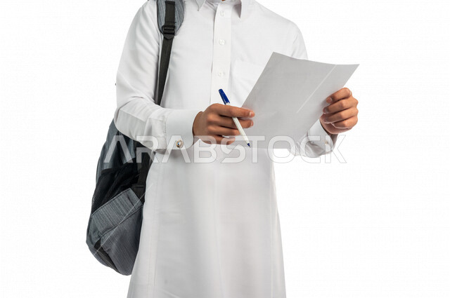 بورتريه لطالب جامعي عربي خليجي سعودي يرتدي الجلابية و الحقيبة الجامعية ، يحمل بيده ورقة وقلم ، الاستعداد للاختبارات ، تعبئة الاستبيانات ،كتابة الملاحظات والتقارير ، متابعة المحاضرات والدروس اليومية ،التعليم في المملكة العربية السعودية، خلفية بيضاء
