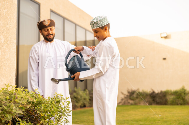 استخدام وعاء السقي في ري النباتات ،  اجواء الطبيعة الخلابة ، قضاء الوقت الممتع في إحدى الشاليهات ، مفهوم النظافة والاهتمام بحديقة المنزل ، رجل عربي خليجي عماني يقضي وقت ممتع مع إبنه بايماءات السعادة ، فعاليات وأجواء ترفيهية ، المتعة و التسليه مع الابناء .