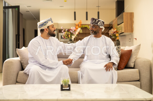 مشاعر الحب والمودة والأبوة ، الاحسان الى الاباء ورد الجميل ، شاب عربي خليجي عماني يرتدي الدشداشة والكمة ، اجواء عائلية دافئة بايماءات وجه سعيدة ، بناء علاقات حميمة مع الابناء .