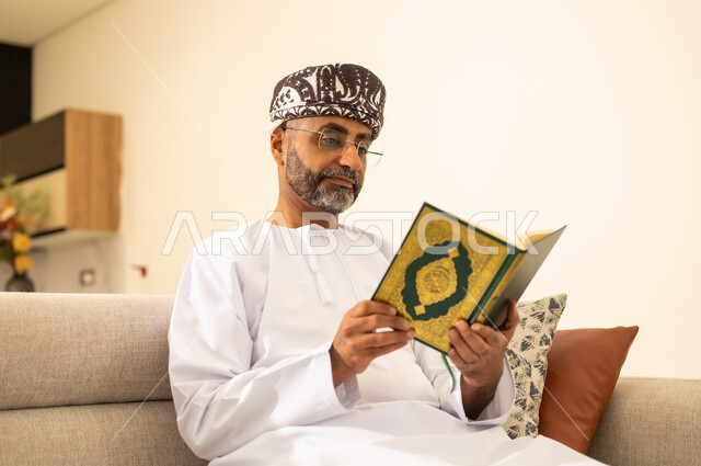 الإكثار من ذكر الله تعالى، التقرب الى الله ، صورة مقربة لرجل عربي خليجي عماني يرتدي الدشداشة والعمامة يحمل بيده المصحف الشريف ، الاجتهاد في العبادة، تلاوة وقراءة القرآن الكريم وتدبر معانيه، الشعور بالخشوع والطمأنينة .