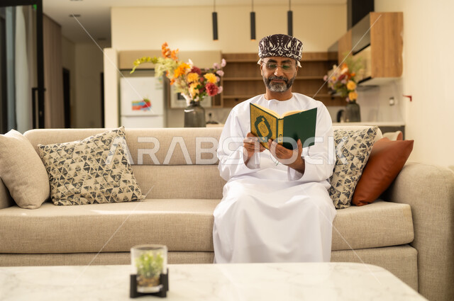 تدبر الآيات القرآنية والتفكر بها، مفهوم العبادة والطاعة والتقرب الى الله ، تلاوة وقراءة القرآن الكريم، رجل عربي خليجي عماني يرتدي الدشداشة والعمامة يحمل بيده المصحف الشريف ، الإكثار من ذكر الله تعالى.