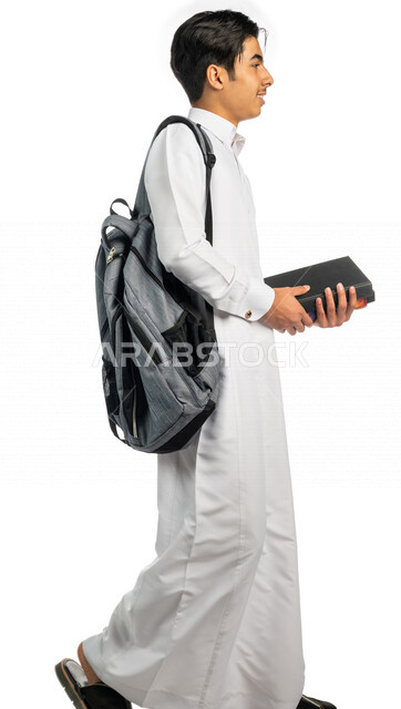 Portrait of a Saudi Arabian Gulf university student wearing a university bag and holding a book in his hand, preparing to go to university, following university lectures, university education in Saudi Arabia, white background
