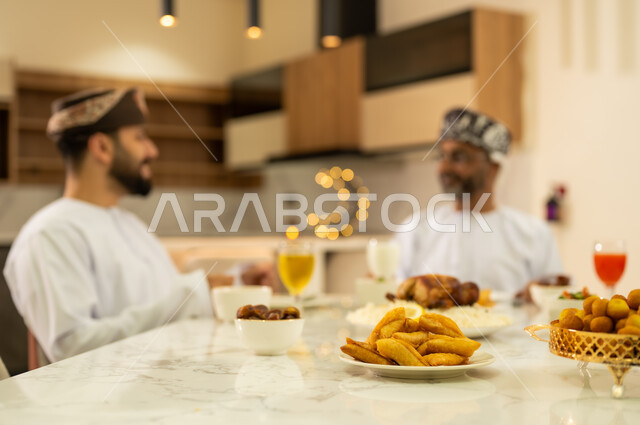 المقبلات والمأكولات الشرقية العربية التقليدية ، العزائم والولائم فى الاعياد والمناسبات الدينية الاسلامية ، اجواء عائلية دافئة بايماءات وجه سعيدة ، عائلة عربية خليجية عمانية تجتمع على مائدة الافطار فى شهر رمضان  ، ديكورات وزينة رمضانية ، شهر الخير والبركة .