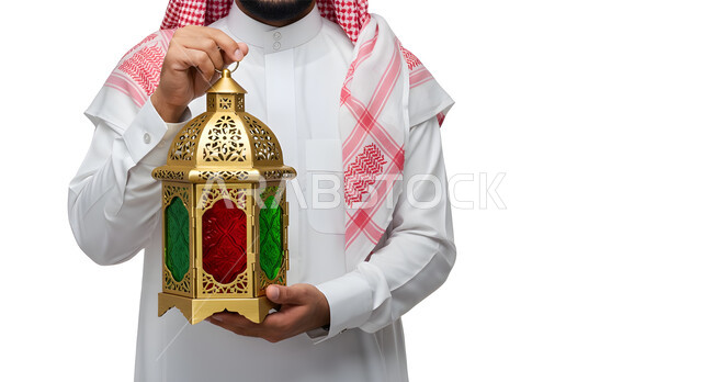 الاستعداد والتجهز لاستقبال شهر رمضان المبارك، الاحتفال بقدوم شهر الخير، بورتريه مقرب ليد رجل عربي خليجي سعودي يرتدي الشماغ والثوب التقليدي يحمل فانوس معدني مزخرف مضيء، زينة وأنوار الأعياد والمناسبات الدينية الاسلامية، خلفية بيضاء