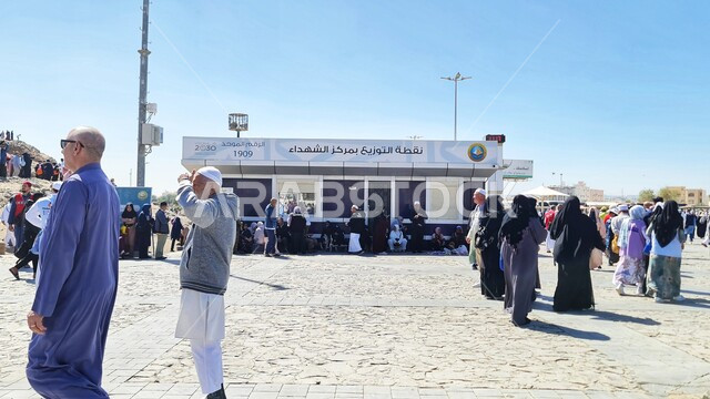 تجمع الحجاج والسياح امام نقاط التوزيع بمركز الشهداء في النهار، معلم ديني اسلامي مقدس في المملكة العربية السعودية، زيارة جبل احد، جذب و استقطاب المسلمين من كافة انحاء العالم، السياحه في الاماكن الدينيه المشهورة