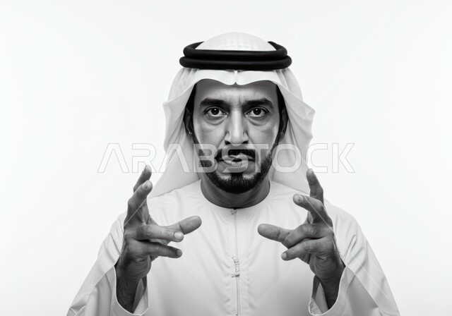 Trying to hold something, looking at the camera with a serious and firm expression, close-up portrait of an Emirati Gulf Arab man wearing a kandura and ghutra raising his hands up, gestures of ignorance and questioning, white background