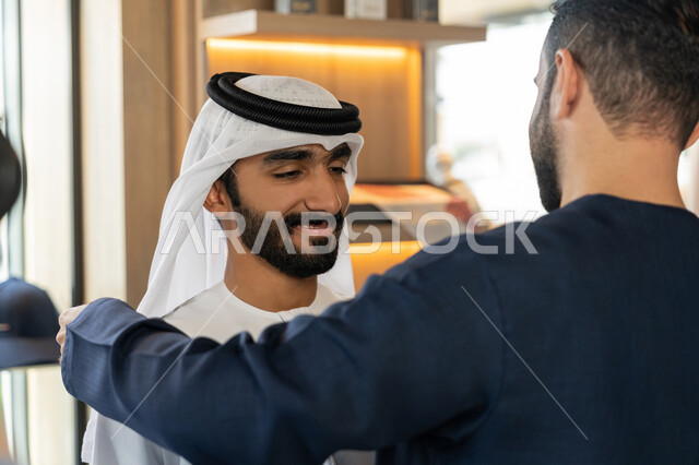 Practicing the tailoring profession, using sewing tools and equipment, handicrafts and crafts, a close-up photo of an Emirati Gulf Arab tailor wearing a blue kandura taking the customer's measurements, choosing the finest fabrics for making dresses, the pleasure of shopping in the mall