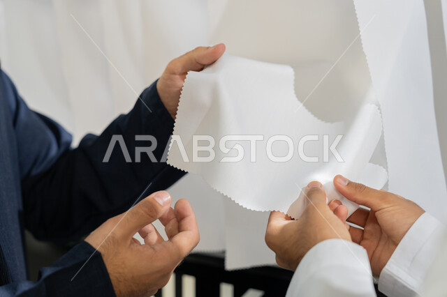 الاستمتاع بالتسوق في المول، عرض الأزياء والموديلات الحديث، استغلال أيام التخفيضات والعروض المشوقه، صورة مقربه ليد رجل عربي خليجي اماراتي يرتدي الكندورة البيضاء يقوم باختيار لون الملابس، اختيار أجود أنواع الأقمشة لصناعة الأثواب،  الجمعة البيضاء