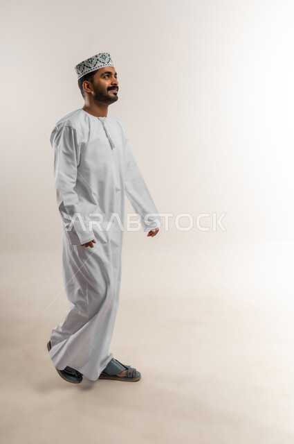 The concept of elegance and interest in external appearance, a side portrait of a young Gulf Arab man wearing a dishdasha and a sleeve with gestures of happiness and pleasure, expressions of walking and walking to go somewhere, a full-length body image, length, white background