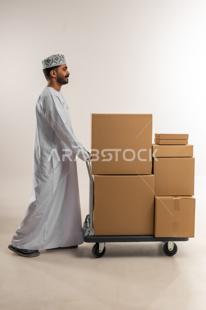 Online shopping and ordering, on-time and accurate delivery, high quality shipping and delivery service, portrait of a young Omani Gulf Arab man wearing a dishdasha and a kumquat holding a closed cardboard box, buying household needs, full body, white background