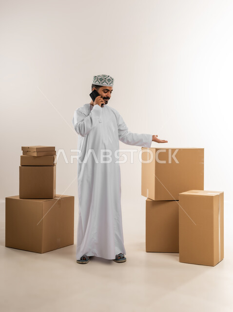 الرد على الاتصالات والاستفسارات من الزبائن, بورتريه لرجل عربي خليجي عماني يرتدي الكمة والدشداشة يعمل في خدمة العملاء في شركة شحن وتوصيل البضائع, توثيق الطلبات من التابلت, تاكيد الحجوزات ادارة عملية خدمات التوصيل السريع, الجسم بالطول الكامل، خلفية بيضاء