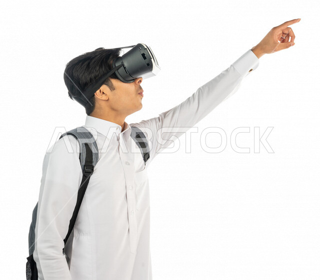 Portrait of a Saudi Arabian Gulf university student wearing 3D virtual reality glasses and pointing with the index finger at something, clicking and pressing, linking virtual reality to education and training, simulating the virtual world, finger movement