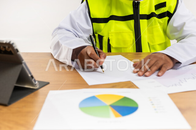 دراسة الرسوم البيانية والاحصاءات، متابعة مخطط الاعمار, العمل في القطاع الهندسي، مفهوم الهندسة والانشاءات المعمارية، بورتريه مقرب لمهندس عربي خليجي عماني يرتدي الدشداشة والكمة وسترة الحماية يمسك بيده التابلت، مهنة ووظيفة للشباب في سلطنة عمان، خلفية بيضاء