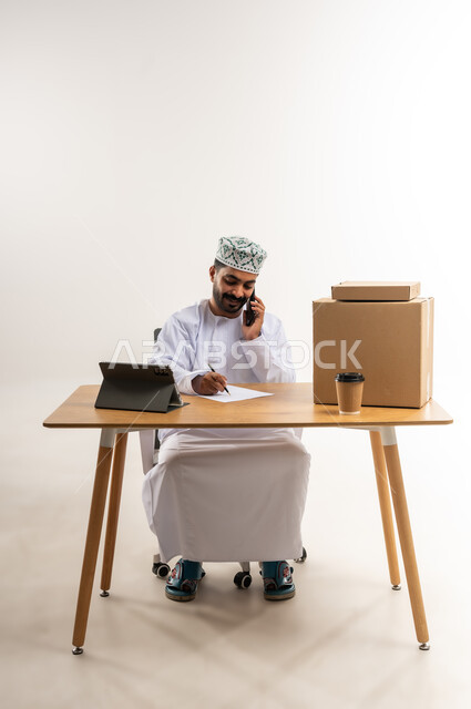 الرد على الاتصالات والاستفسارات, كتابة وتدوين طلبات الزبائن, بورتريه لرجل عربي خليجي عماني يرتدي الكمة والدشداشة يعمل في خدمة العملاء في شركة شحن وتوصيل البضائع, توثيق الطلبات من التابلت, تاكيد الحجوزات ادارة عملية خدمات التوصيل السريع, خلفية بيضاء