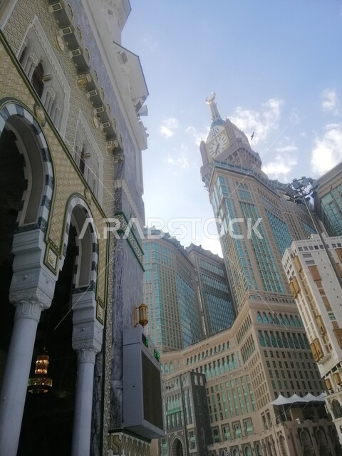 مبنى برج الساعة الملكي في مكة المكرمة، الفن الهندسي المعماري لناطحات السحاب، معلم ديني إسلامي مقدس، بيت الله الحرام في الحرم المكي الشريف في المملكة العربية السعودية، منظر الغيوم في السماء في النهار، العبادة والتقرب إلى الله