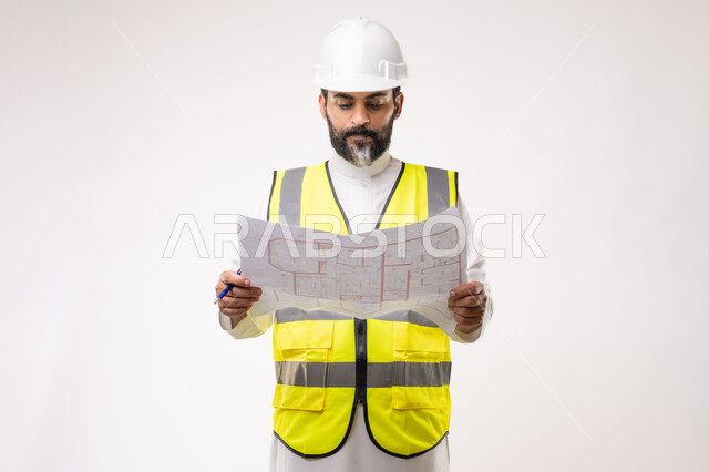 Engineering and construction project management, concept of planning and construction project study, youth engineering profession and job, portrait of a Saudi Arabian Gulf engineer wearing traditional thobe, jacket and protective helmet working in the engineering sector in the Kingdom of Saudi Arabia, white background