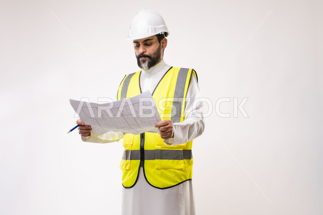 Engineering and construction project management, concept of planning and construction project study, youth engineering profession and job, portrait of a Saudi Arabian Gulf engineer wearing traditional thobe, jacket and protective helmet working in the engineering sector in the Kingdom of Saudi Arabia, white background