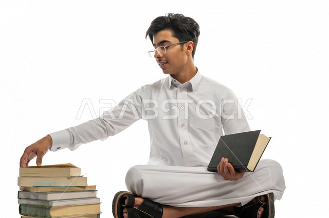 Portrait of a Saudi Arabian Gulf university student choosing a book from a group of university books, studying for university exams, reviewing daily lessons, university education in the Kingdom of Saudi Arabia