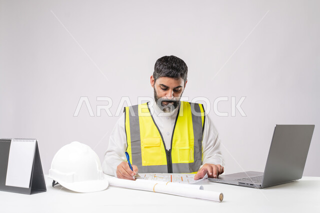 Integrating technology and technology in the field of engineering, working in the engineering sector in the Kingdom of Saudi Arabia, the concept of engineering and construction project management, a youth profession and job, a portrait of a Saudi Arabian Gulf engineer wearing a traditional thobe and jacket working on a laptop, white background