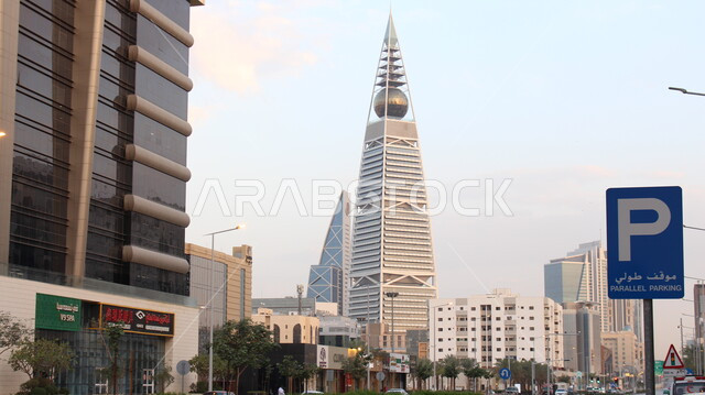 برج الفيصلية في العاصمة الرياض في النهار، التطور والتقدم العمراني للمنشأت في المملكة العربية السعودية، التصاميم الهندسية المعمارية على الطراز الحديث والمتطور، منظر السماء الزرقاء الصافية، مكان سياحي مشهور، الفن الهندسي للابراج وناطحات السحاب