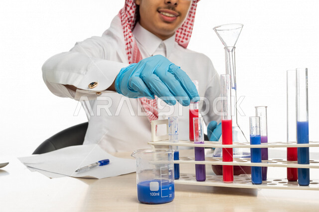 بورتريه لطالب جامعي عربي خليجي سعودي يرتدي الزي الخليجي التقليدي ،يجلس في معمل الكيمياء ، استخدام انابيب الاختبار لاجراء التجارب في المختبر ، التفاعلات الكيميائية ،البحث والتطوير ، مفهوم الكيمياء الحيوية