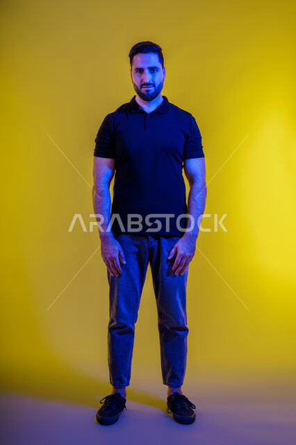الثقة بالنفس والرجولة لشاب إماراتي أنيق يقف بإستقامة واعتدال، بورترية من الخلف لرجل عربي خليجي سعودي يرتدي الزي الكاجوال، كامل الجسم، خلفية صفراء