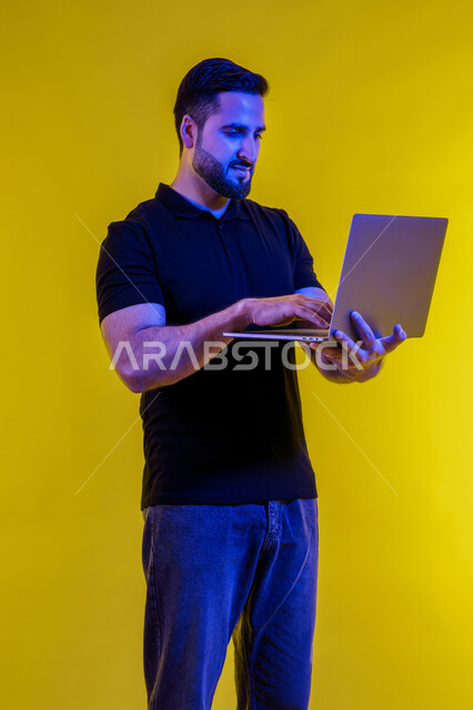 Making a video call using a laptop, portrait of a young Emirati Gulf man in casual clothes, a Saudi Arabian man browsing the internet, using modern technical devices, remote work, electronic marketing, professions and jobs, holding a business meeting via laptop, yellow background
