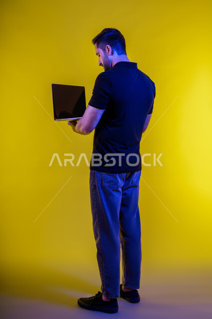 Making a video call using a laptop, portrait of a young Emirati Gulf man in casual clothes, a Saudi Arabian man browsing the internet, using modern technical devices, remote work, electronic marketing, professions and jobs, holding a business meeting via laptop, yellow background