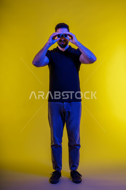 Seeing distant objects using a telescope, a Saudi man looking through binoculars, a full-length portrait of a young Arab Gulf Emirati man wearing casual clothes, yellow background, using binoculars and the love of exploration and adventure, planning for future goals and ambitions