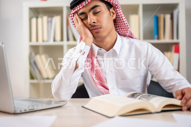 طالب جامعي عربي خليجي سعودي يرتدي الزي الخليجي التقليدي ،يجلس في مكتبة الجامعة وامامه كتاب ،ايماءات الوجه واليد تدل على الملل والارهاق ، عدم الحصول على الكتاب الملائم ،استعارة الكتب ، اثراء التعليم الجامعي ، البحث العلمي ، مفهوم التعليم والتعلم