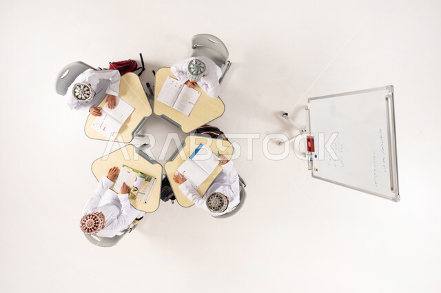 Group activities for teaching students in Omani schools, Gulf Arab Omani students wearing traditional dishdasha and kummah sitting on school desks, vertical overhead portrait of a Gulf Arab Omani teacher giving lessons on a whiteboard, interest in the educational process, white background