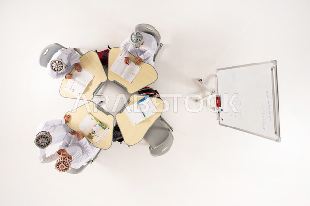 انشطة جماعية لتعليم الطلاب في المدارس العمانية، تلاميذ عرب خليجيون عمانيون يرتدون الدشداشة التقليدية والكمة يجلسون على مقاعد الدراسة، بورتريه علوي عامودي لمعلم عربي خليجي عماني يقوم بإعطاء الدروس على اللوح الابيض، الاهتمام بالعملية التعليمية، خلفية بيضاء