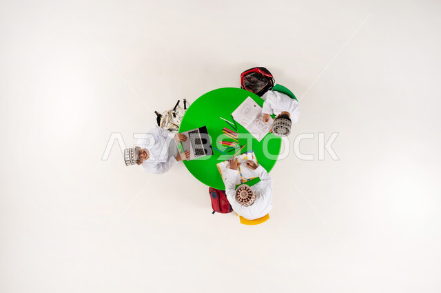 Enhancing students' artistic creativity, an entertaining and fun activity, learning concentration and innovation skills via laptop, vertical overhead portrait of Omani Gulf Arab students wearing dishdashas and kummah drawing, coloring, and using modern technical devices, white background