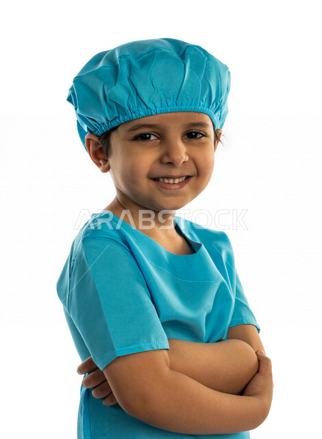 Portrait of a smiling Saudi Arabian Gulf Arab boy, wearing an operating uniform, looking at the camera, with crossed hands, different face and hands gestures, wearing a blue robe, the little doctor, dreaming of becoming a doctor, future profession, white