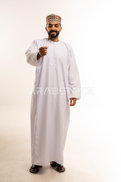 التأكد من نظافة الأسنان بعد تناول الطعام، الاهتمام بالأناقة والمظهر الخارجي، المحافظة على ابتسامة بيضاء، بورتريه  لرجل عربي خليجي عماني يقوم بتنظيف أسنانه باستخدام الخيط السني، مفهوم العناية بصحة الفم، صورة الجسم بالكامل، خلفية بيضاء .