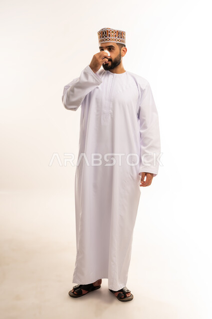 وعي الرجل العربي بأهمية العناية الشخصية، التخلص من الرؤوس السوداء والجلد الميت، مفهوم  الاهتمام بنضارة وتحسين البشرة، استخدام ماسكات تنظيف المسام ومكونات تجميلية، بورتريه لرجل عربي خليجي عماني يرتدي الدشداشة والكمة يضع لصقات الأنف ، مكونات تجميلية شبابية، الجسم بالطول الكامل ، خلفية بيضاء .