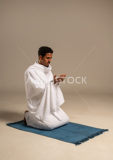 Supplication with humility and supplication, asking for forgiveness and pardon from God, portrait of an Arab Gulf man wearing Ihram clothes raising his hands up, performing Hajj and Umrah rituals, getting closer to God through worship and obedience, white background
