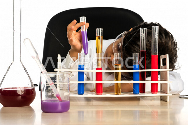 Portrait of a Saudi Arabian Gulf boy, wearing a white coat, using test tubes to conduct experiments, conducting chemical experiments and reactions in the laboratory, experiments and scientific research, studies and analyzes, chemicals, future profession,