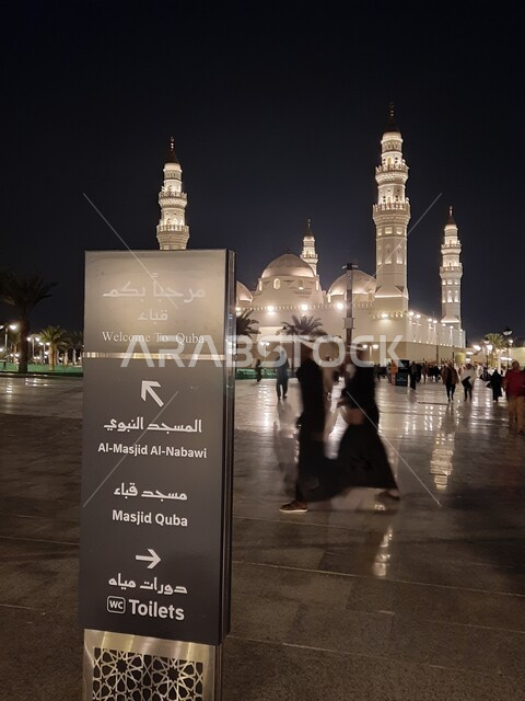 لافتة دلالية ارشادية للمعالم المحيطة بمسجد قباء في المدينة المنورة في الليل، معلم ومكان ديني مقدس في المملكة العربية السعودية، العبادة والتقرب إلى الله، الفن الهندسي المعماري على الطراز الإسلامي للمآذن والقبب، أداء فريضة الصلاة على وقتها