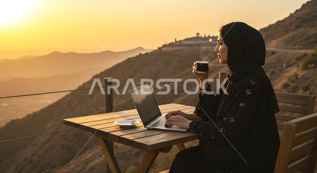 الاستمتاع بتناول المشروب الساخن, ايماءات التركيز والاندماج، إنجاز المهام في وسط الصحراء والرمال الذهبية, إدارة وتنظيم الأعمال في الأجواء الطبيعية, امرأة عربية خليجية سعودية محجبة تستخدم الحاسب المحمول، خلفية الطبيعة الصحراوية