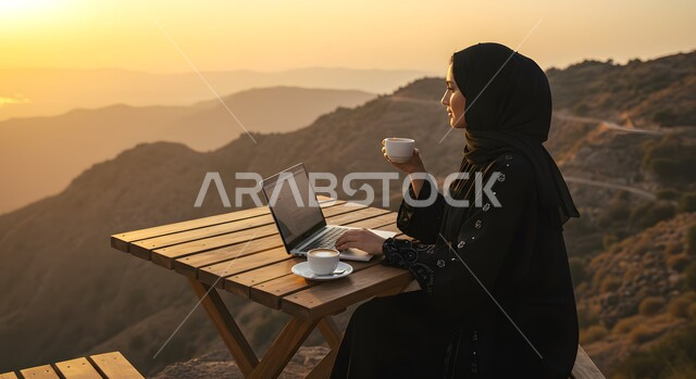الاستمتاع بتناول المشروب الساخن, ايماءات التركيز والاندماج، إنجاز المهام في وسط الصحراء والرمال الذهبية, إدارة وتنظيم الأعمال في الأجواء الطبيعية, امرأة عربية خليجية سعودية محجبة تستخدم الحاسب المحمول، خلفية الطبيعة الصحراوية