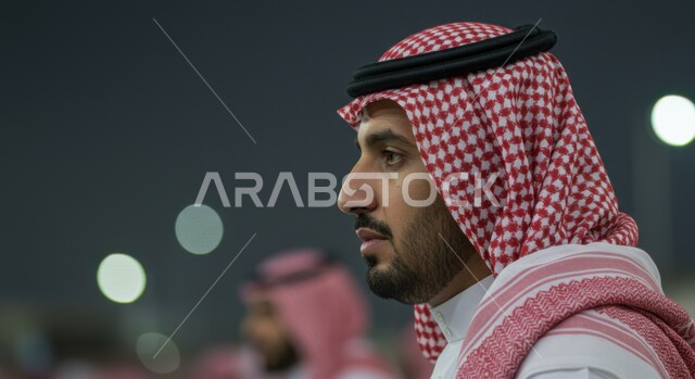 الاهتمام بالمظهر الخارجي، صورة مقربة من الجانب لرجل عربي خليجي سعودي يرتدي الثوب التقليدي والشماغ ينظر إلى شيء ما بإيماءات التركيز، مفهوم الأناقة والرجولة