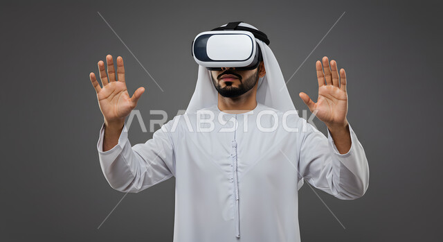 التفاعل مع الفيلم ومحاكاة العالم الخيالي، بورتريه مقرب لشاب عربي خليجي اماراتي يرتدي الكندورة والغترة يضع نظارات الواقع الافتراضي ثلاثية الأبعاد, ايماءات تدل على الاندماج والمتعة, خلفيه رمادية