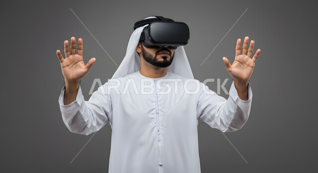 التفاعل مع الفيلم ومحاكاة العالم الخيالي، بورتريه مقرب لشاب عربي خليجي اماراتي يرتدي الكندورة والغترة يضع نظارات الواقع الافتراضي ثلاثية الأبعاد, ايماءات تدل على الاندماج والمتعة, خلفيه رمادية